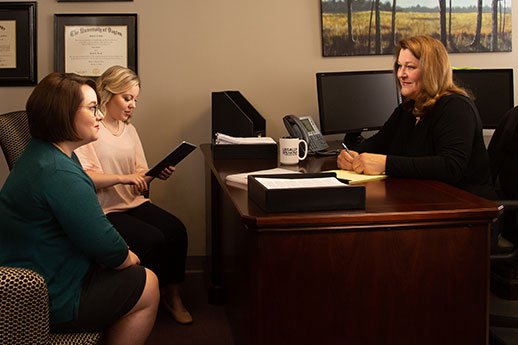 Personal Injury Attorney Robin Hewitt from Crocker Law Firm talks with two female case managers in her office