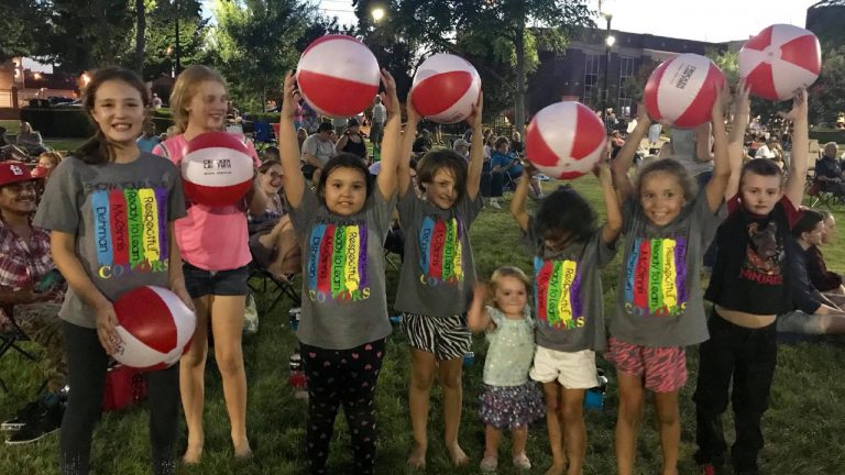 Kids at Bowling Green's Concerts in the Park hold up Crocker Law Firm Injury Attorney beach balls over their head