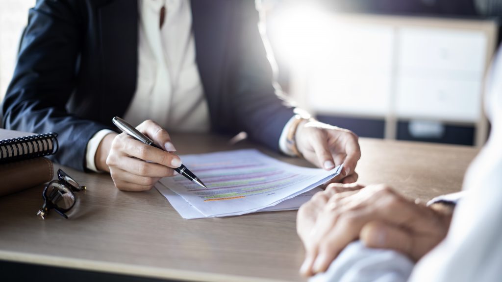 White female reviewing a legal document with a white male. They are discussing the benefits of hiring an attorney