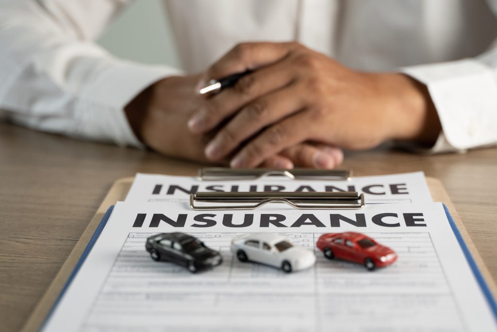 African American Male hands with a document in front of him that says "insurance" on it. PIP is important to add to your insurance plan.