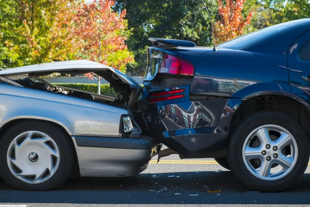 Photo of a silver car rear-ending a black car, causing property damage to both vehicles.