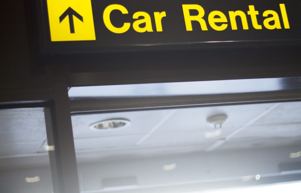 Airport information car rental sign light panel giving directions in departure lounge.